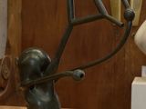 une statue représentant un homme tenant un objet circulaire posé sur une table