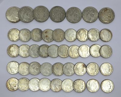 a close up of a pile of silver coins on a white surface