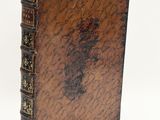 an old book with a brown cover sitting on top of a white surface