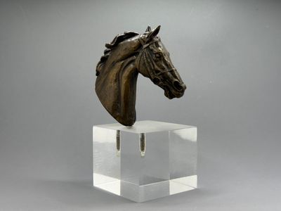 une tête de cheval en bronze posée sur un socle en acrylique transparent