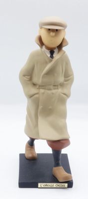 figurine représentant un homme en manteau et chapeau, debout sur un socle noir