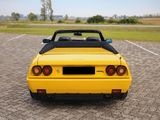 the back end of a yellow sports car parked in a parking lot