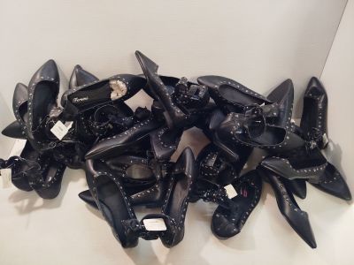une pile de chaussures noires posées sur une surface blanche