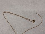 a gold necklace with a ball on it laying on the floor