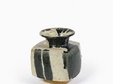 un vase noir et blanc posé sur une surface blanche