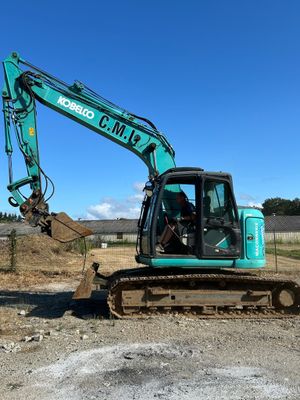 une pelleteuse verte garée au milieu d'un champ de terre