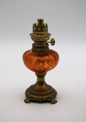 une image représentant une lampe en verre rouge posée sur un pied, sur une surface blanche