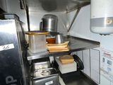 a small kitchen with a stove and a shelf with pots and pans on it