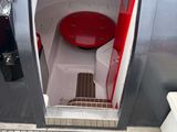 a red and white toilet in a boat with the door open
