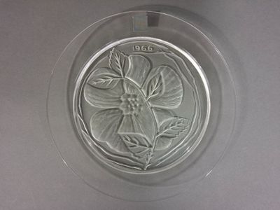 une assiette en verre ornée d'une fleur, posée sur une table