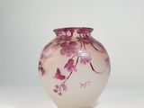 a glass vase with purple flowers on it on a white surface