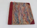 un gros plan d'un livre posé sur une surface blanche, avec une couverture rouge