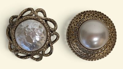 pair of silver and mother of pearl brooches on a white background