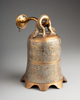 an antique brass bell with a bird on top of it