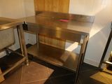 a stainless steel table in a kitchen with a wooden wall behind it