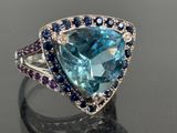 an image of a ring with a blue topazr surrounded by blue sapphires and purple sapphires