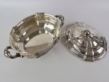 two silver dishes on a white table with a silver lid