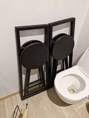 a toilet with two stools next to it in a bathroom