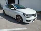 La voiture blanche est garée sur le parking près de l'immeuble.