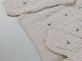 a white sweater with blue buttons on it sitting on a table