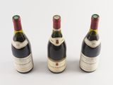 three bottles of wine are lined up on a white surface