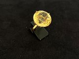 bague en diamant jaune posée sur un socle noir, sur une surface noire