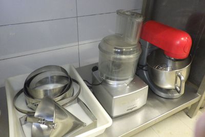 trois robots ménagers posés sur une étagère métallique dans une cuisine
