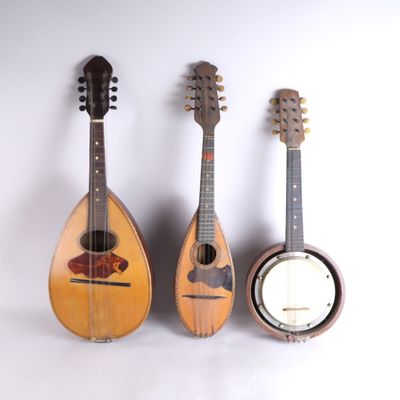 trois guitares et un banjo sont alignés contre un mur blanc