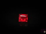 a square red ruby stone on a black surface
