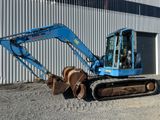 une petite pelleteuse bleue garée devant un immeuble