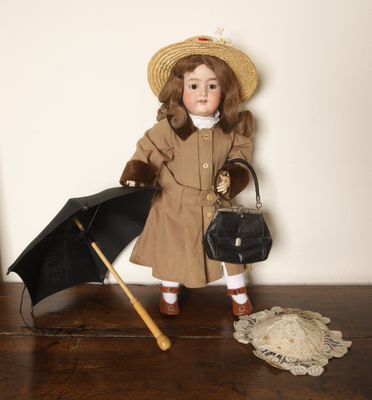 une poupée avec un parapluie et un chapeau, posée sur une table