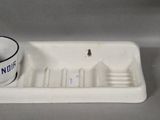 a white porcelain sink with a blue and white cup on it