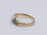 a close up of a gold ring with a pearl and turquoise stone