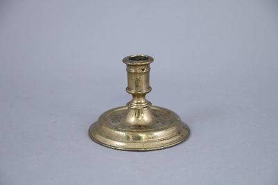 an antique brass candle holder on a white background