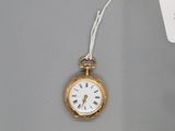 une petite montre de poche en or à laquelle est attachée une étiquette