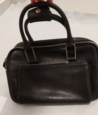 Le petit sac noir est posé sur la table, à côté d'une paire de ciseaux.