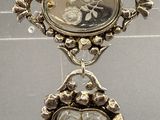 a silver brooch with a picture of a man and a woman on it