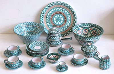 de nombreuses pièces de poterie bleues et vertes posées sur une table