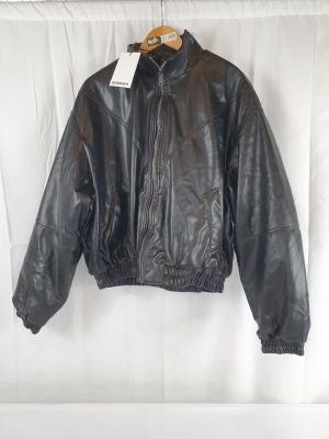 une veste en cuir noir suspendue à un cintre sur un mur blanc