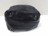 black leather handbag with gold studded handles on a white surface