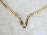 gold plated necklace with a single diamond on a marble surface