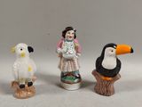 three figurines of people and a bird on a stump