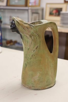 a green vase with a dog head on it on a table