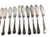 six spoons and six knives on a white surface