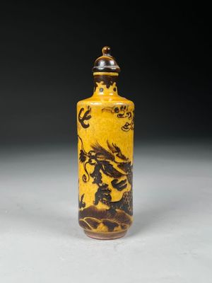 yellow and black glass snuff bottle with a dragon on it
