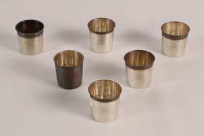 six silver cups are arranged in a circle on a white surface