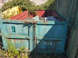a blue dumpster sitting in a yard next to a wooden fence