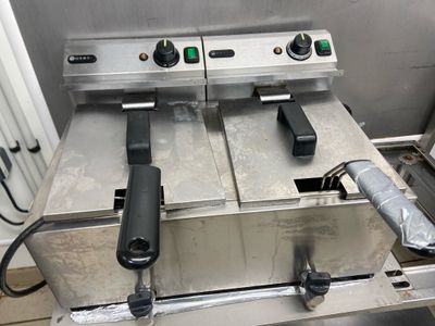 two deep fryers sitting on a table in a kitchen