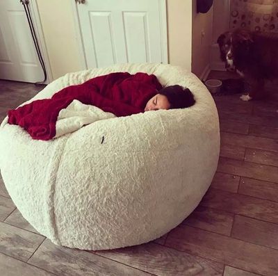 a woman laying on a bean bag chair in a living room