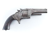 un vieux pistolet est posé sur une surface blanche, devant un fond blanc